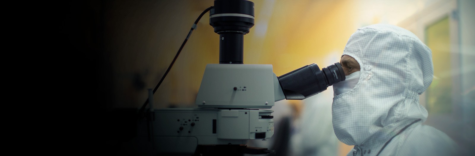 A man uses a compound microscope symbolizing Wolfspeed's dedication to quality.