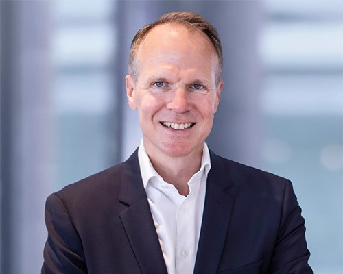 Professional portrait of Wolfspeed CEO and board member Robert Feurle. He wears a black suit and white dress shirt without a tie.