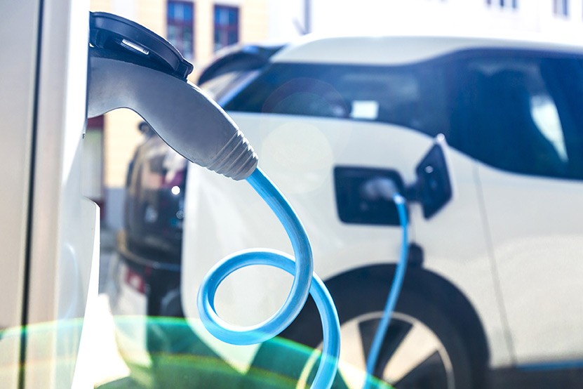 A close up of an electric car being charged at a wall socket