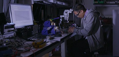 A lab worker looking into a microscope representing Wolfspeed's passionate and innovative employees.