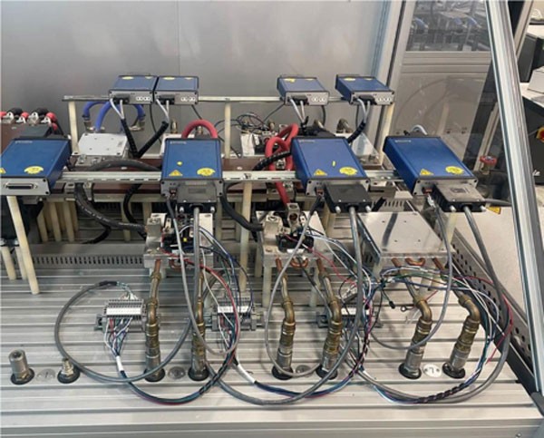 Photograph showing 4 blue boxes housing components. The boxes are set in 2 rows and they are all connected to each other. This shows how Wolfspeed can test up to 12 half-bridge power modules at once. 