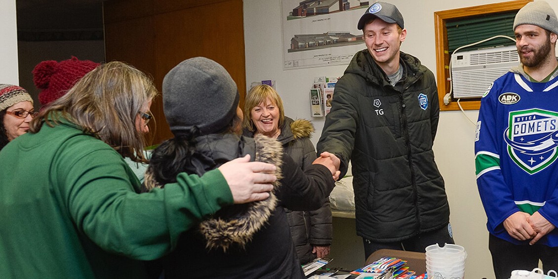 A member from the Utica Comets, Utica City Football Club, and Wolfspeed team shakes hands with someone from the Utica Rescue Mission in New York