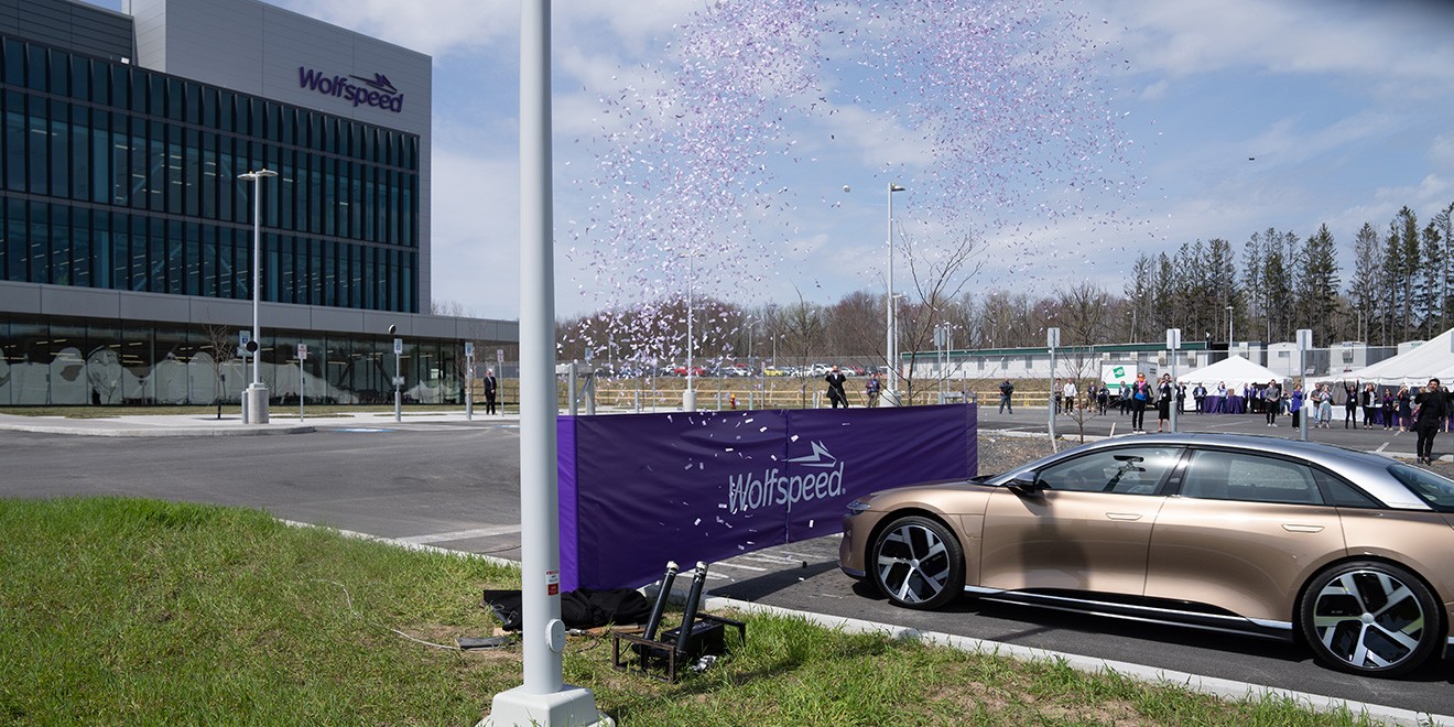 Landscape photo of a champagne colored electric vehicle being used to cut the ribbon on Wolfspeed's newest facility.
